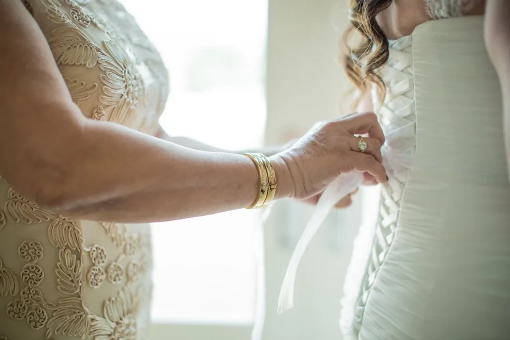 Crop faceless mother lacing up classy wedding dress on daughter