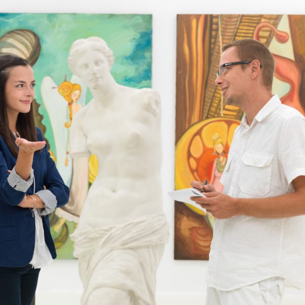 man discussing his art work to a woman
